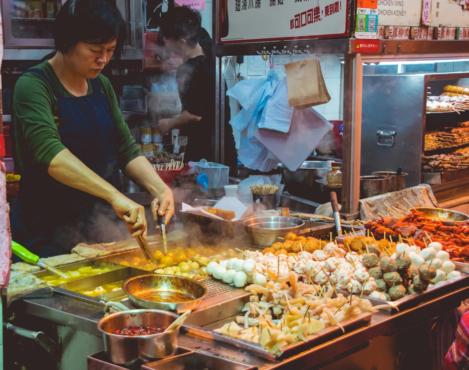 Street food vendor preparing skewers and fish balls at a night market stall
