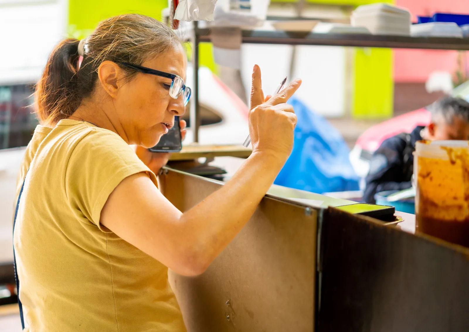 Woman gesturing while ordering food at a counter